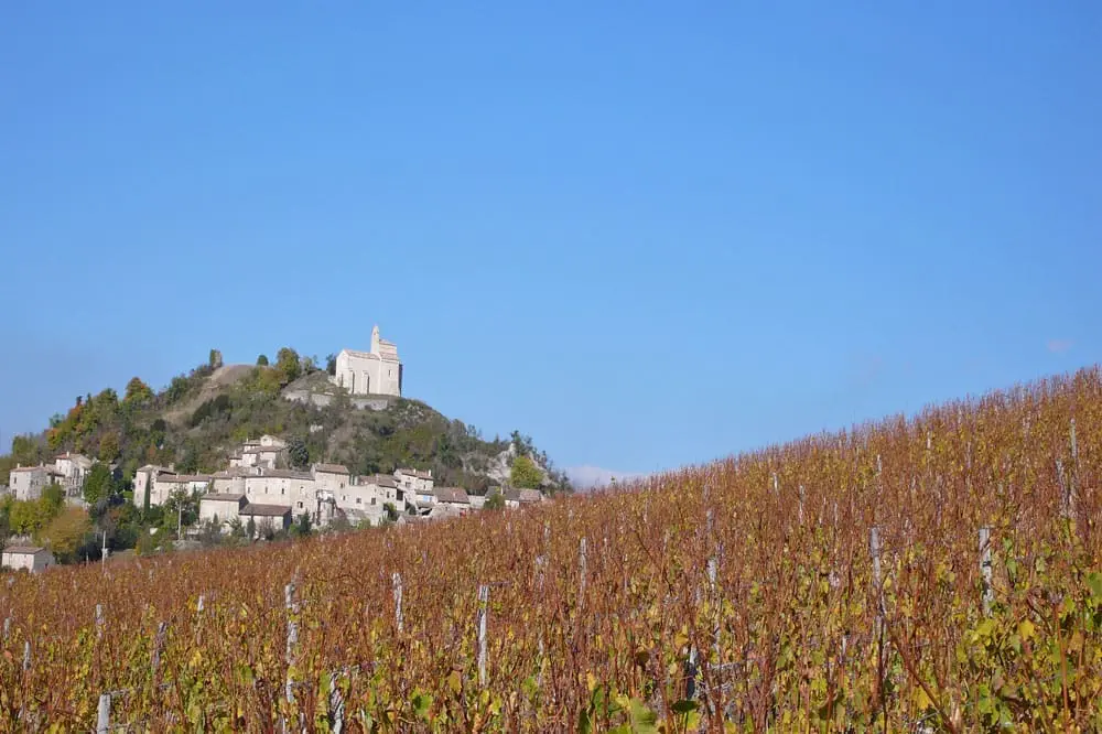 Photographie d'un village perché et de vignobles dans la Drôme