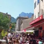 Photographie d'une fontaine en pierre et d'un bar typique du sud de la France